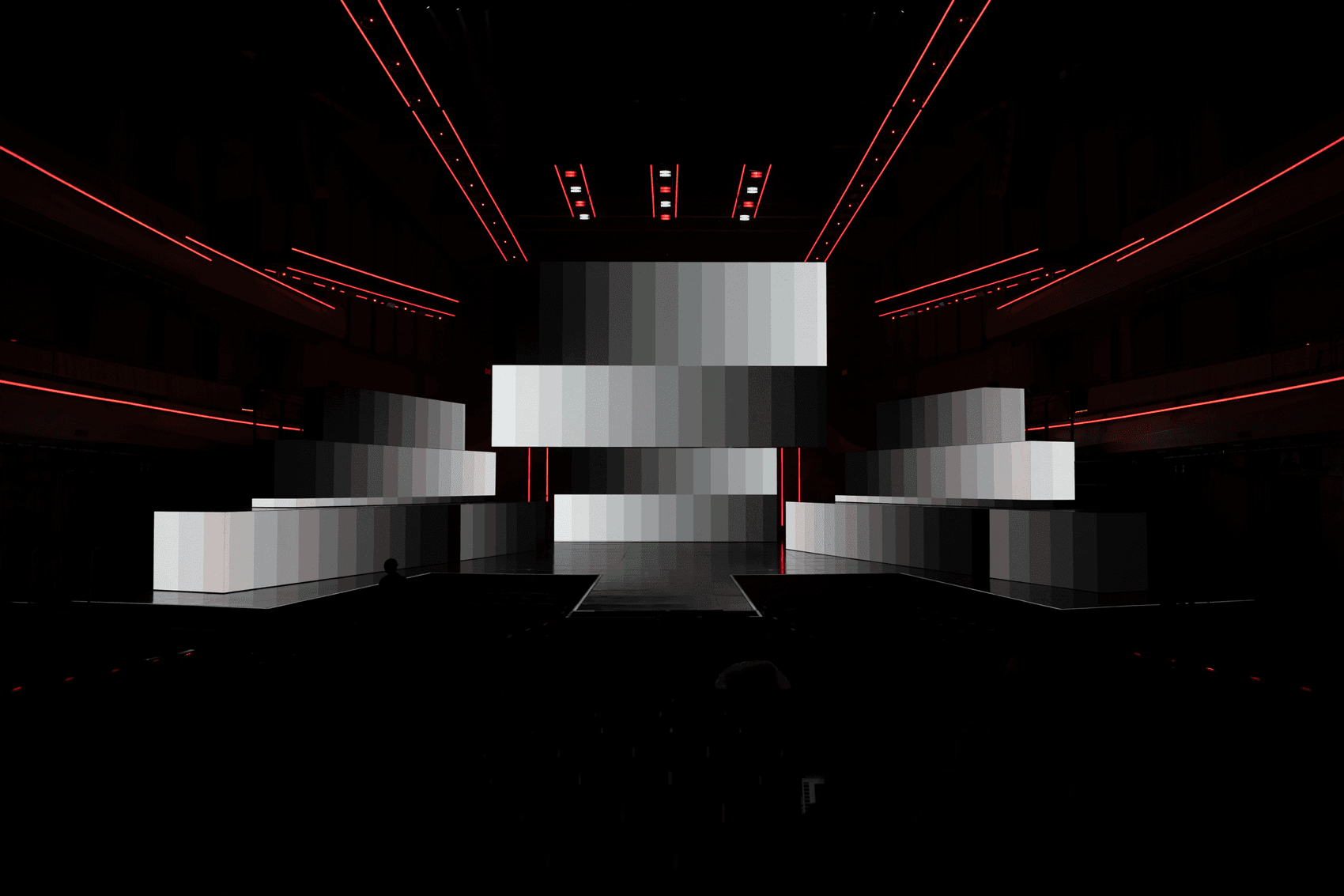 Empty stage set with staggered white rectangular panels lit dimly from below.