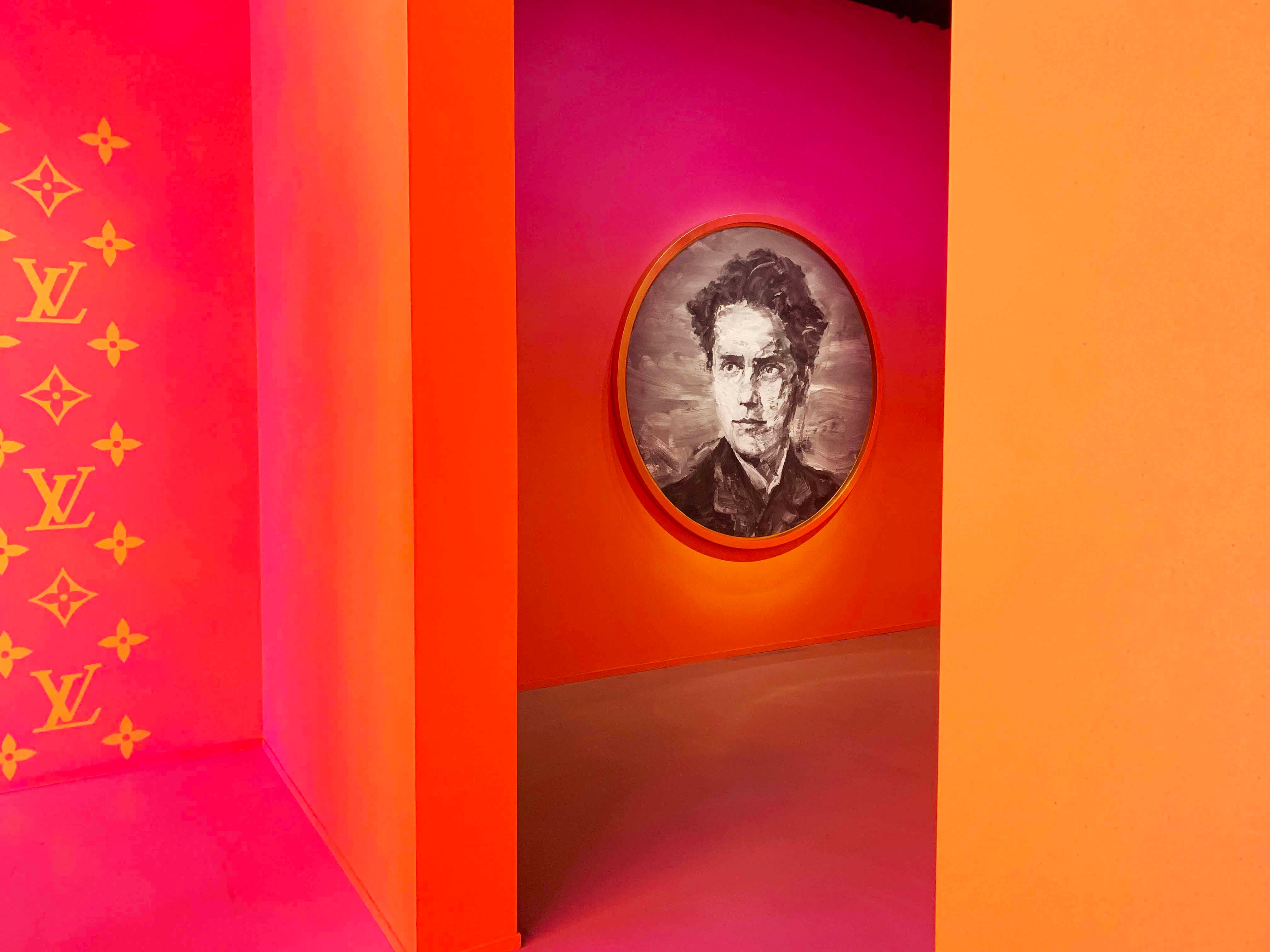 Orange and pink alcove with an oval portrait painting mounted on the wall.