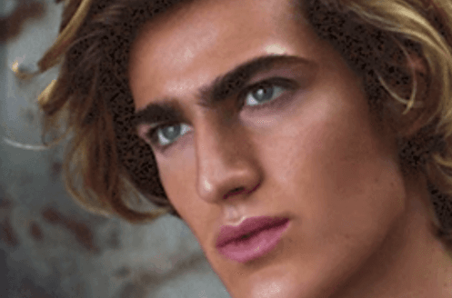 Close-up digital portrait of a young man with tousled blond hair and green eyes.