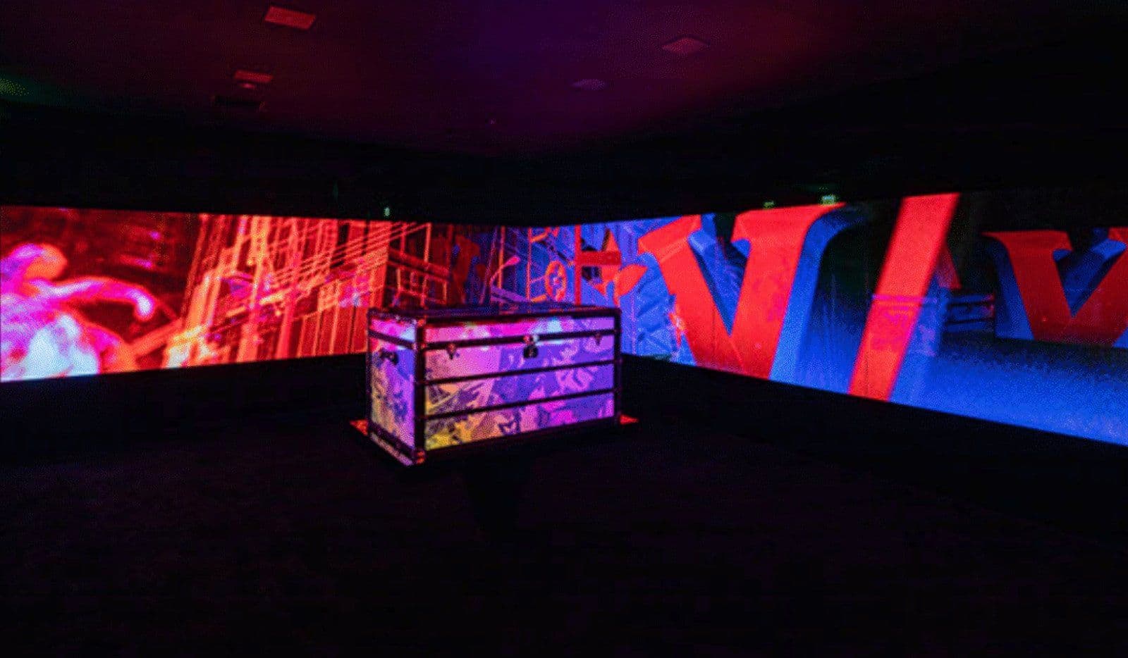 Dark exhibition hall with illuminated red letter sculptures and a lit glass display case.