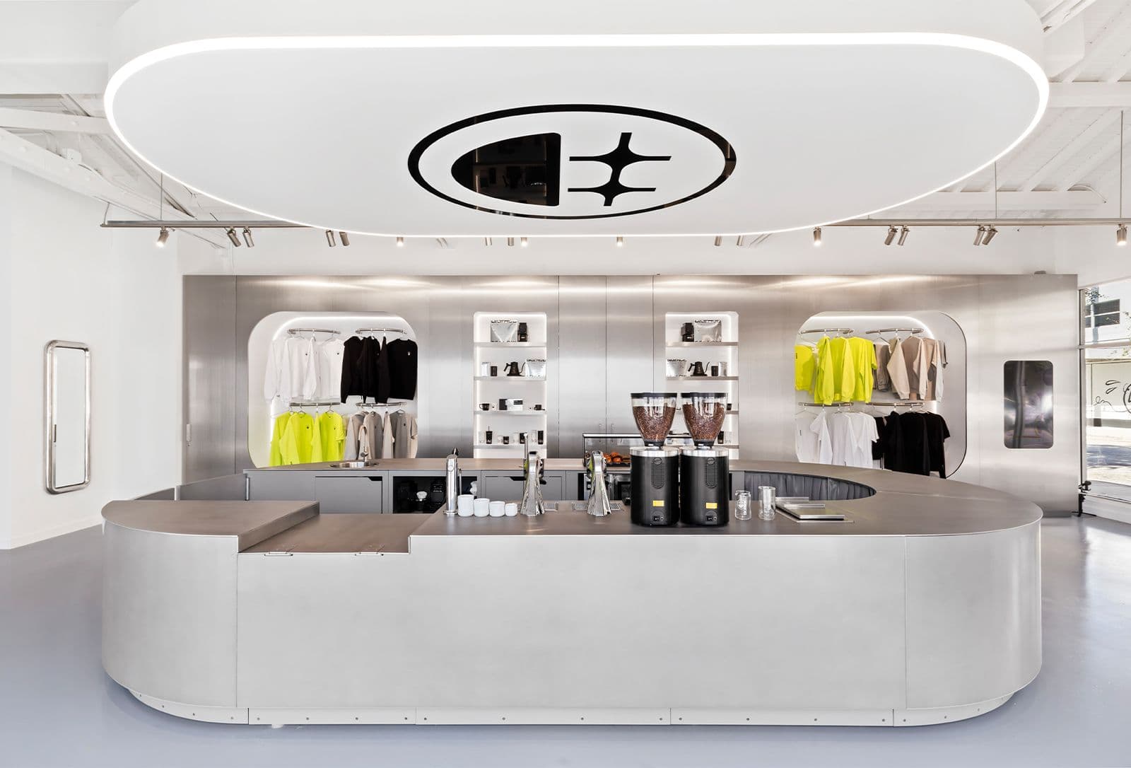 Store counter and wall shelving displaying yellow and black apparel beneath an oval ceiling light bearing the Bigface logo