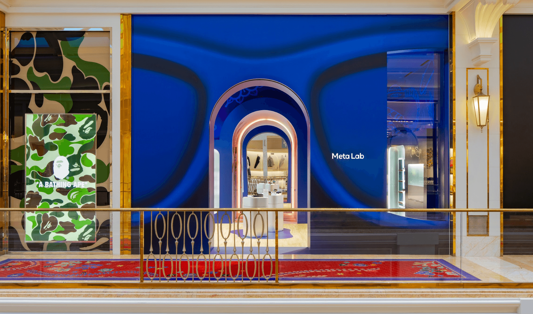 Storefront display window with a blue swirl graphic, a camo-patterned side panel, and a 'MetaLab' sign above an arched doorway, red patterned carpet in the foreground.
