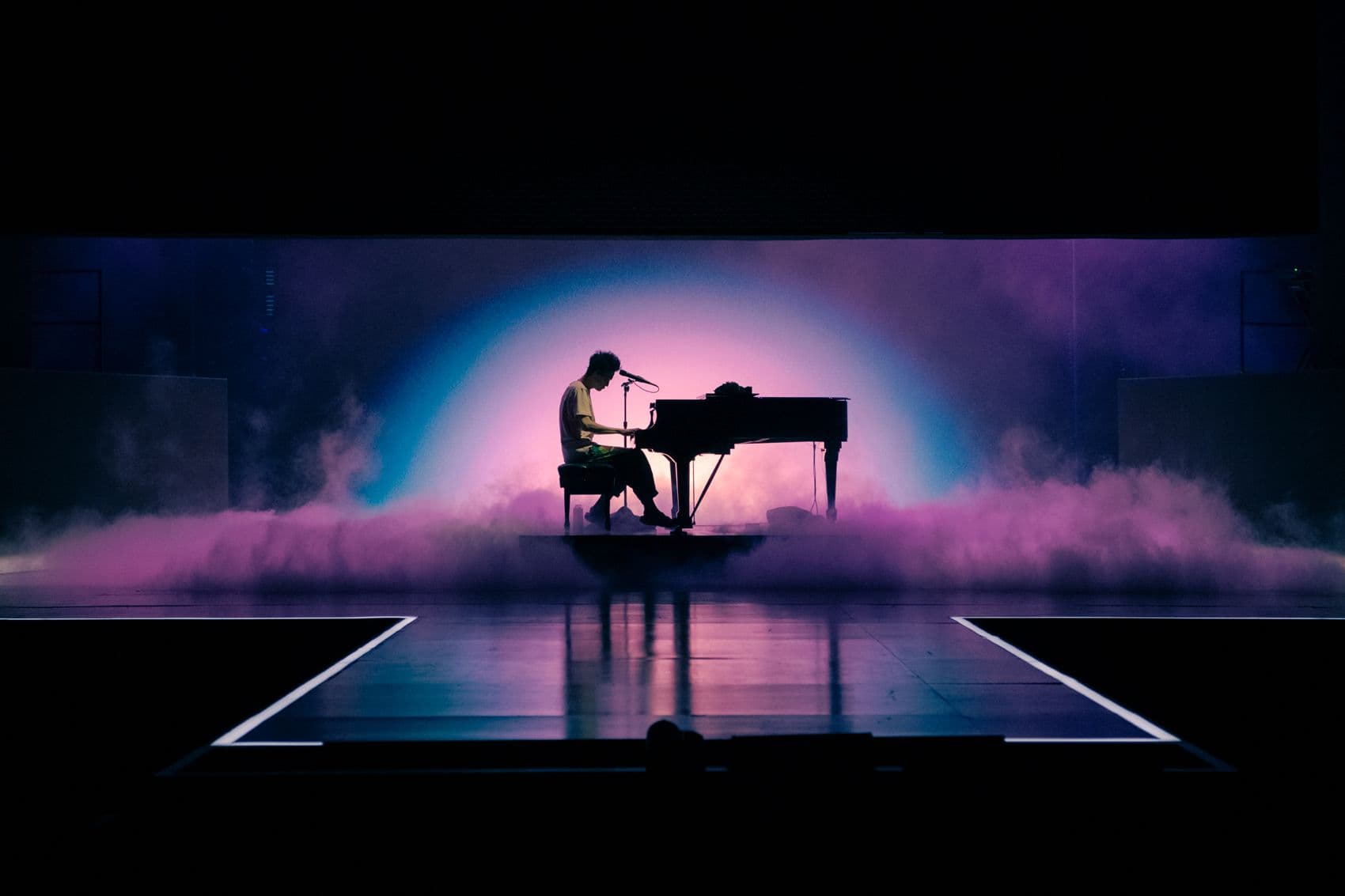 Silhouetted pianist performing on a foggy, purple-lit stage.