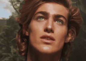 Close-up digital portrait of a young man with wavy brown hair looking upward against a green backdrop.