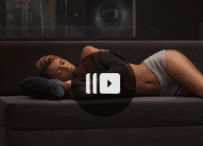 Woman in underwear lying back on a dark couch.