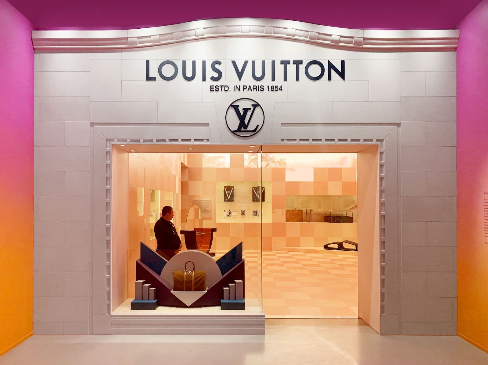 Illuminated Louis Vuitton storefront entrance at night with glass facade and LV signage.